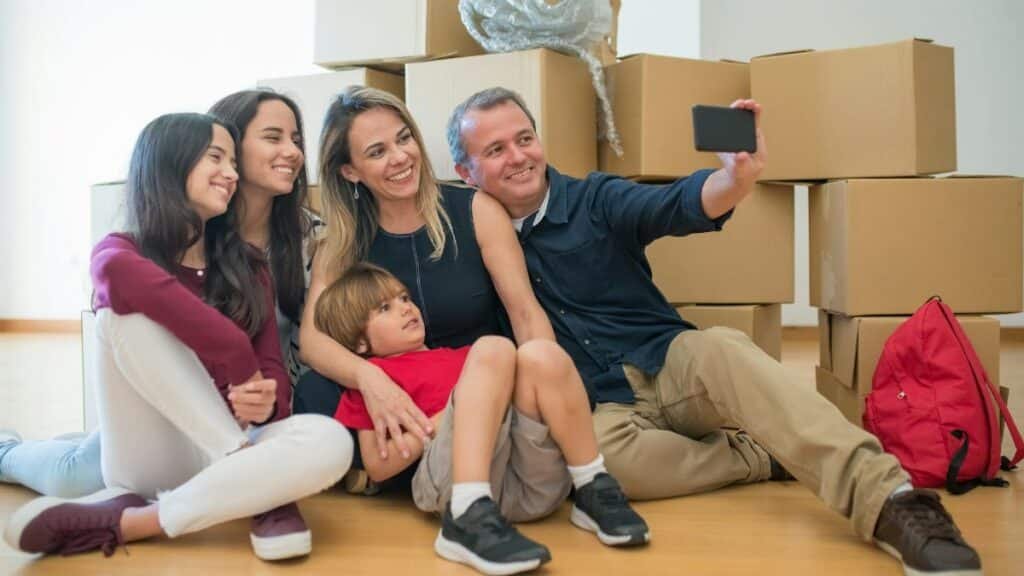A joyful family capturing a selfie while surrounded by moving boxes in their new home.