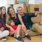 A joyful family capturing a selfie while surrounded by moving boxes in their new home.