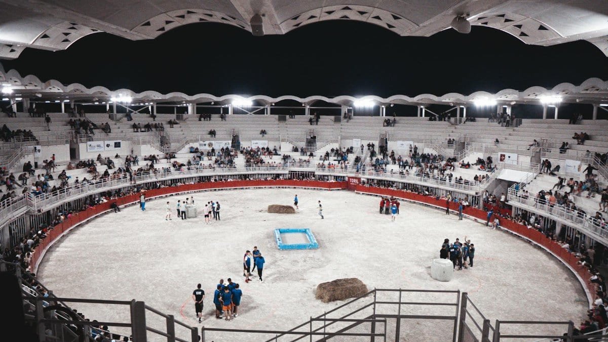 A lively scene at an indoor sports arena filled with spectators and participants at night.