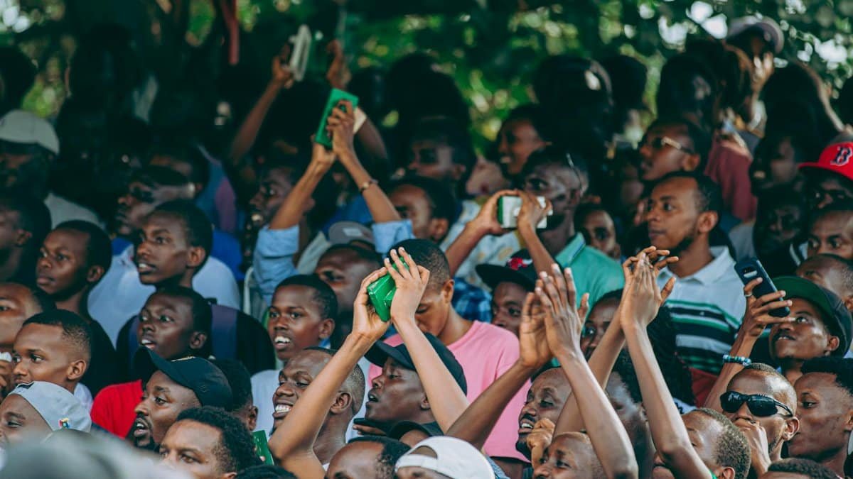 Lively crowd with hands raised celebrating at an outdoor event. Excitement fills the air.