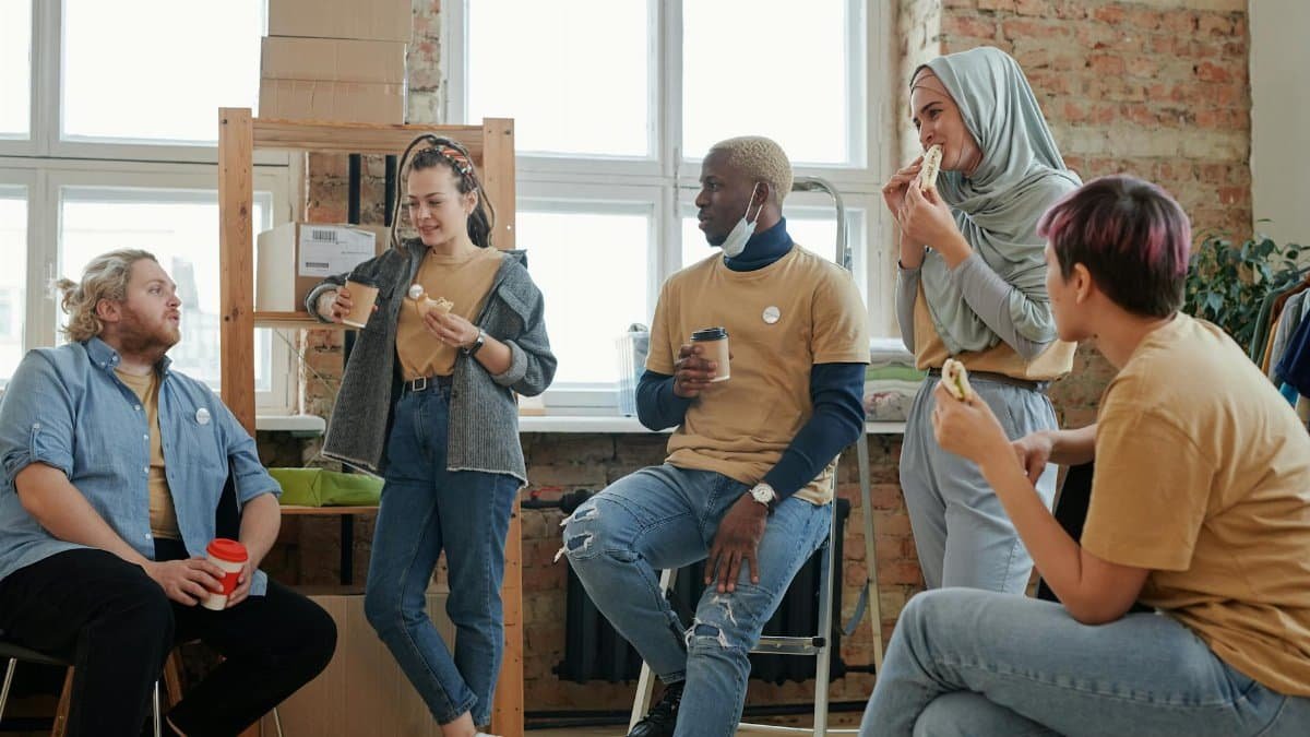 A diverse group of volunteers enjoying a break and socializing indoors. Perfect for community-themed projects.