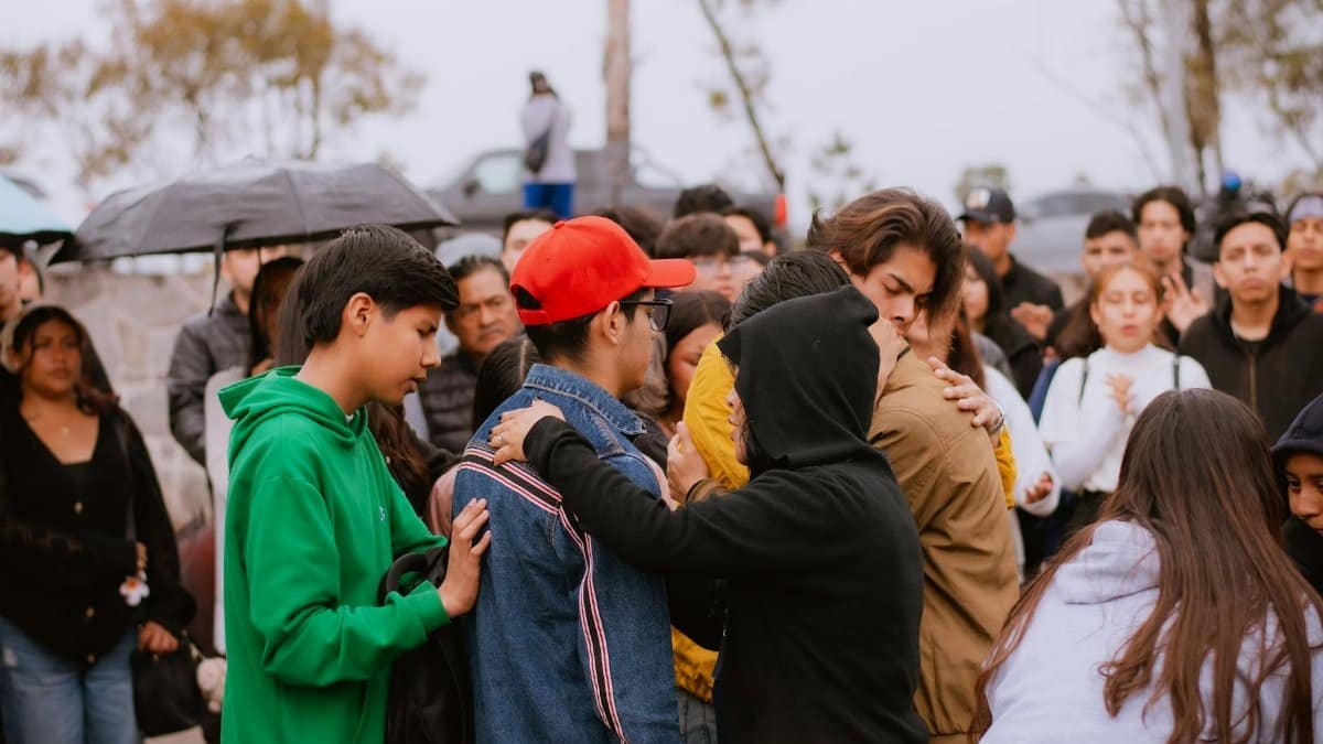 A group of people gather outdoors, offering comfort and support to one another.