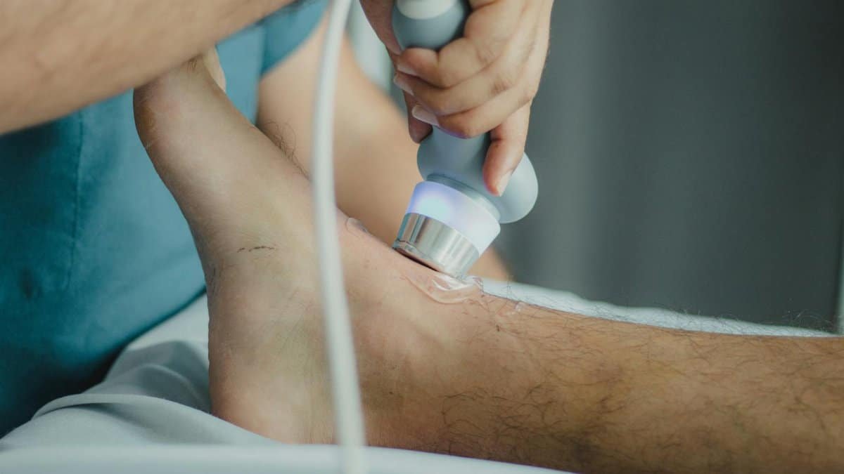 Professional physiotherapist using ultrasound device for leg treatment.