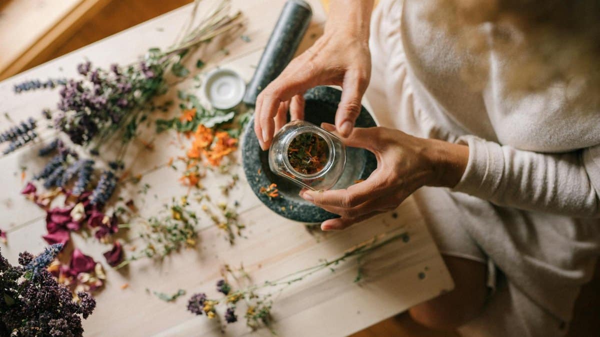 Hands preparing dried flowers and herbs in a mortar. Ideal for holistic and wellness themes.
