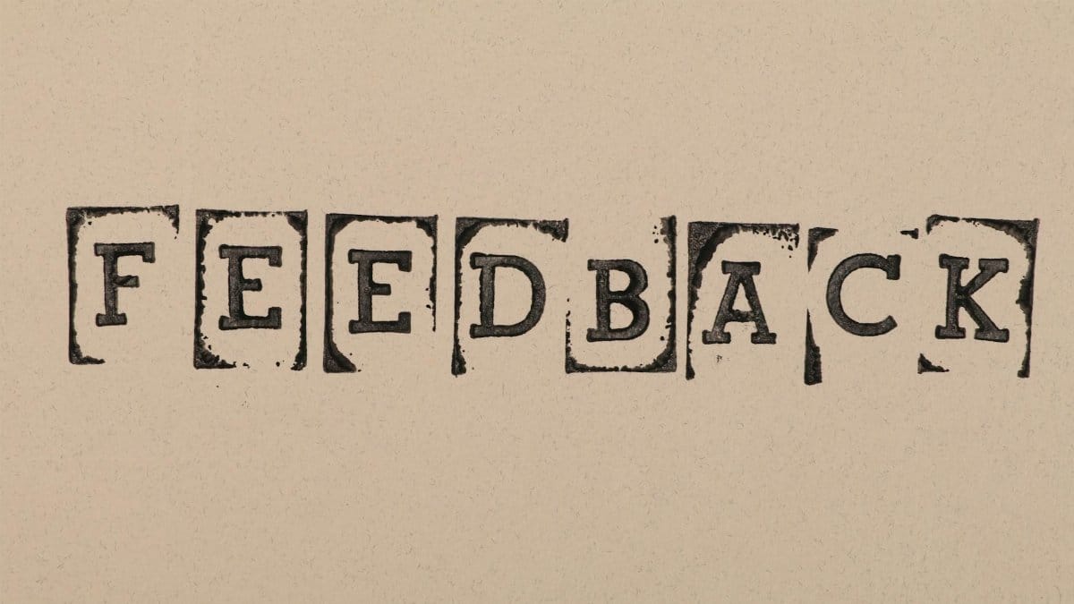 Vintage-style stamped letters spelling 'Feedback' on textured paper background.