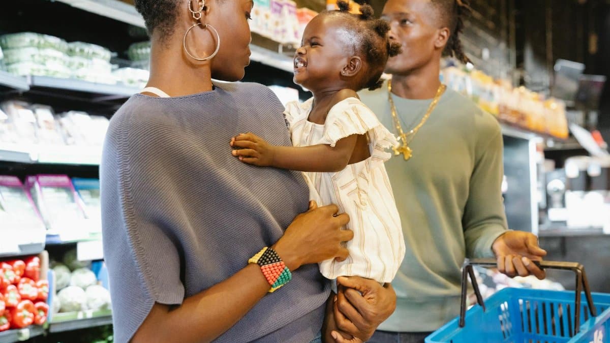 Happy family shopping together in a grocery store, focusing on parenthood and bonding.
