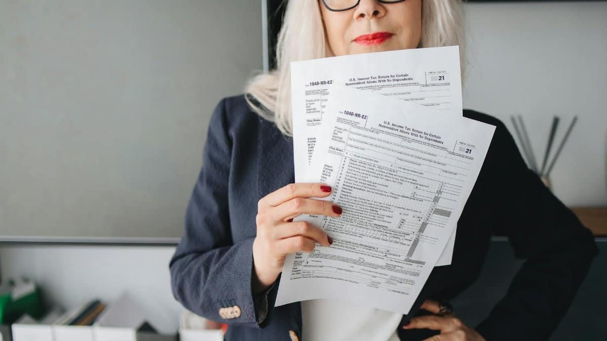 Businesswoman presenting tax documents in a modern office setting.