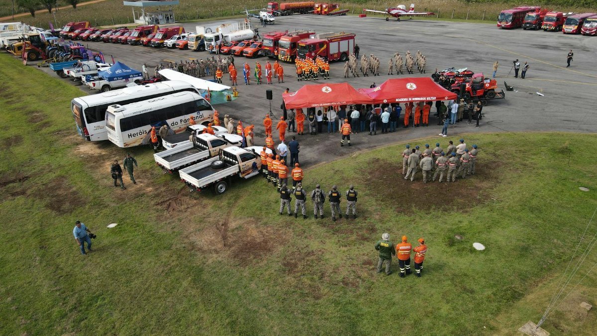 Aerial shot of firefighters coordinating at an outdoor meeting area with vehicles and equipment.