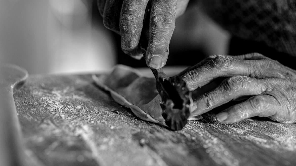 Black and white close-up of hands skillfully crafting homemade pasta.