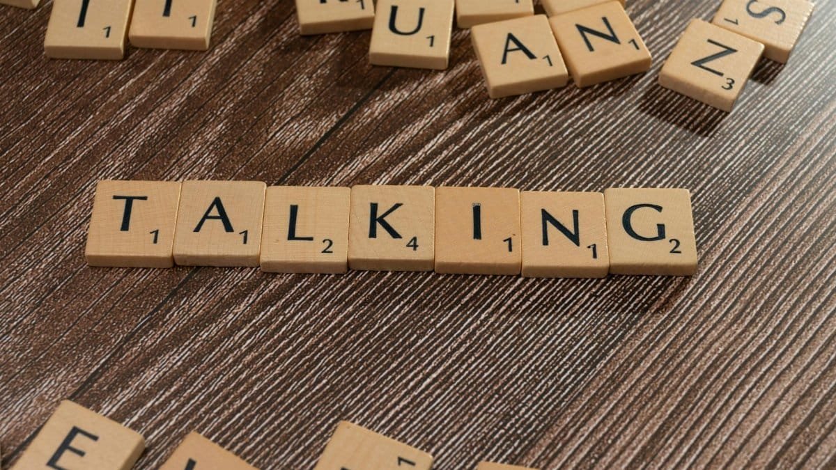 Scrabble tiles spelling 'Talking' on wooden surface, symbolizing communication.