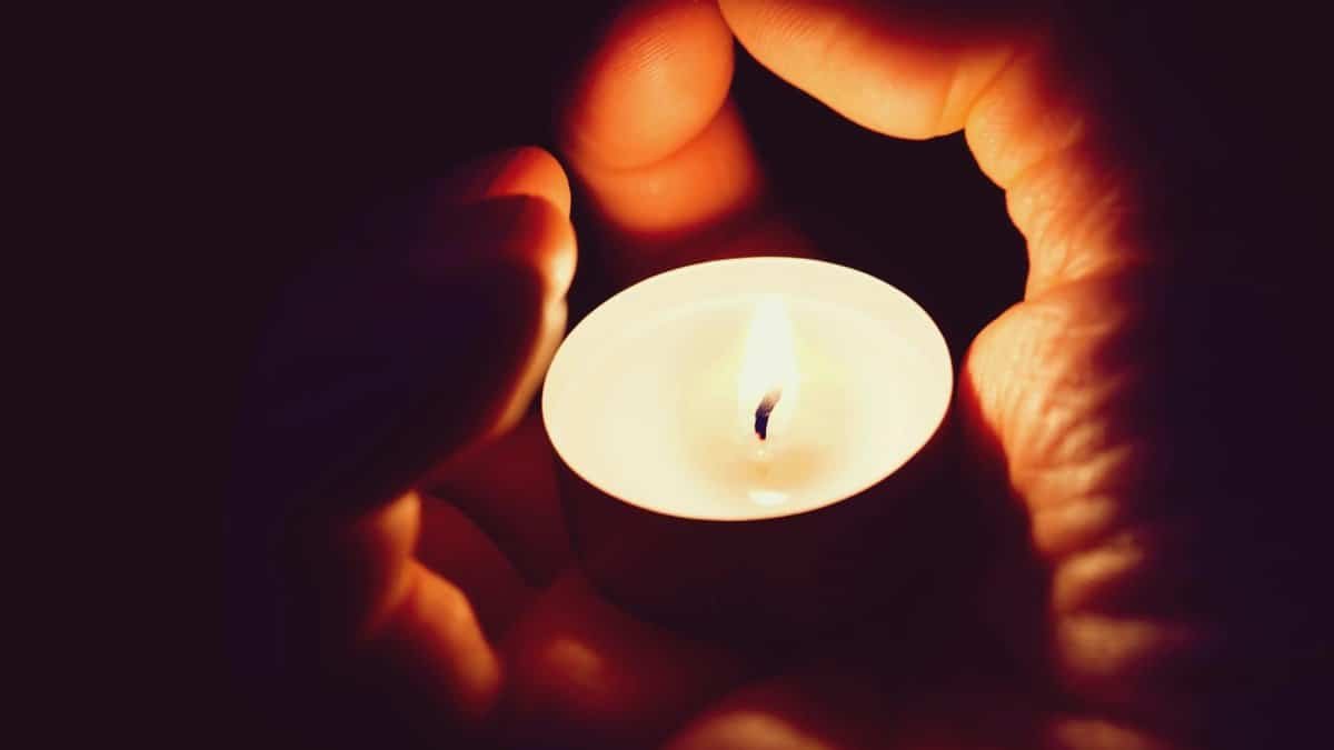 A pair of hands cradling a candle creating a soft and warm illumination.