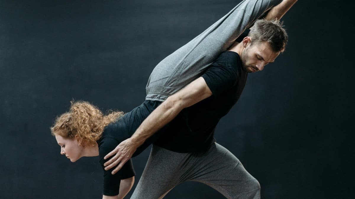 A male and female dancer in a dynamic pose during a rehearsal, showcasing strength and flexibility.