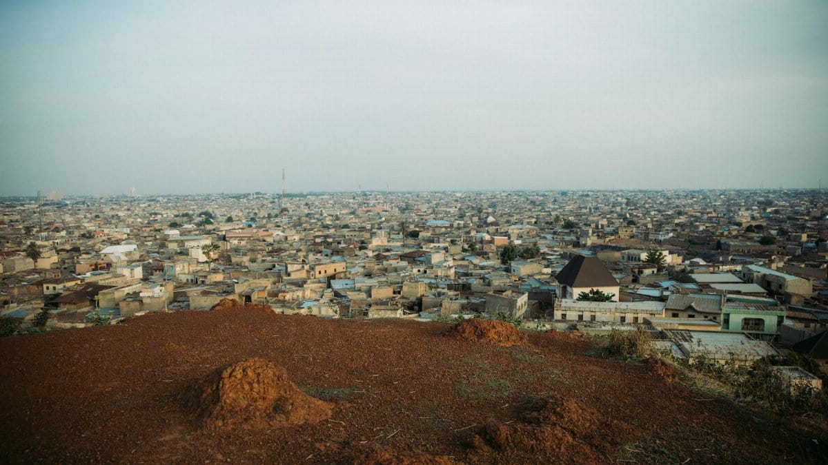 Aerial view of an expansive urban area with a foreground of earthy terrain and distant cityscape.