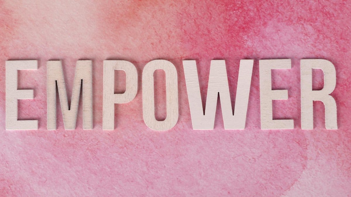 Wooden letters spelling 'EMPOWER' on a pink watercolor background.