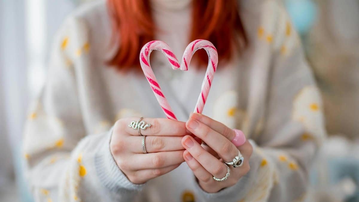 Close-up of a woman holding candy canes in a heart shape, perfect for holiday themes.