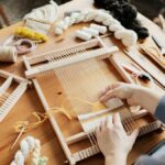 A person weaving textiles using a wooden hand loom, showcasing creativity and craftsmanship.