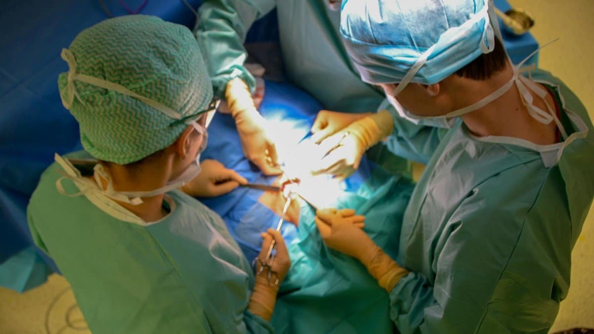 Surgeons in sterile attire performing surgery with precision in a hospital operating room.