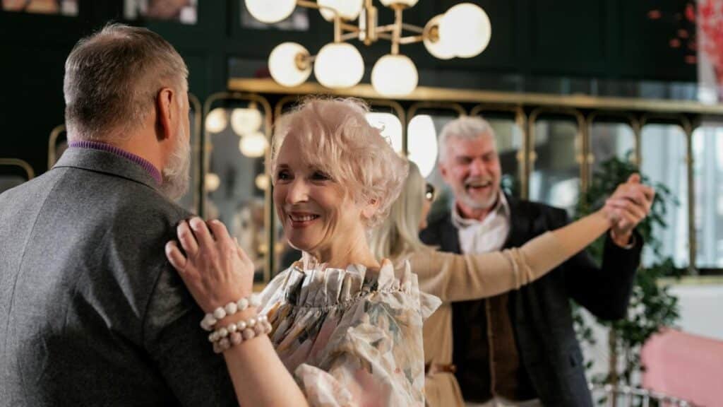 Joyful elderly couples dancing indoors, celebrating togetherness and romance.