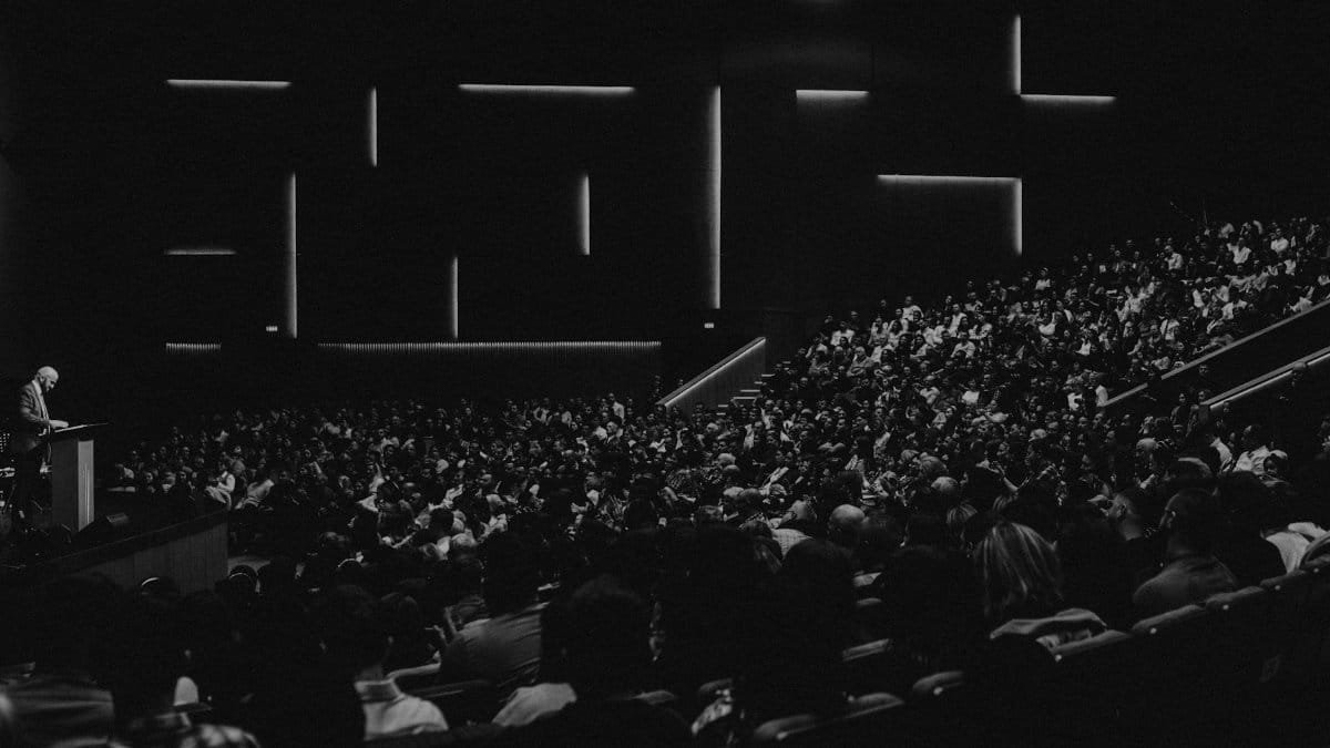 Black and white photo of a large audience in an auditorium with a speaker at the lectern in Oradea.