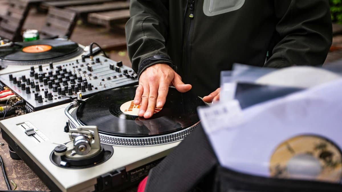DJ spinning vinyl on a classic turntable outdoors, creating music with vintage charm.