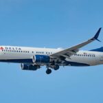 A Delta Air Lines Boeing 737 captured in flight against a clear blue sky near Los Angeles.