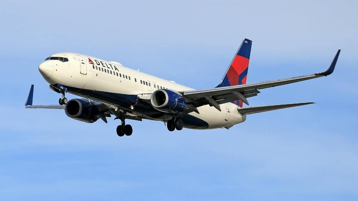 Delta Airlines aircraft soaring in clear blue sky, showcasing aviation travel.