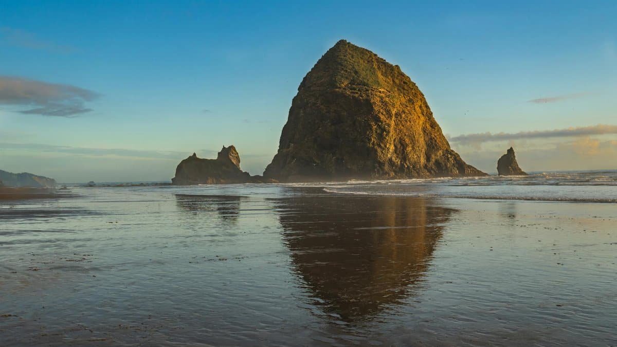 Scenic view of Haystack Rock reflecting on the tranquil waters of Cannon Beach in Oregon, USA.