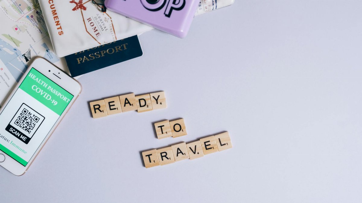 Travel essentials including passport, map, and health passport app ready for post-pandemic journeys.