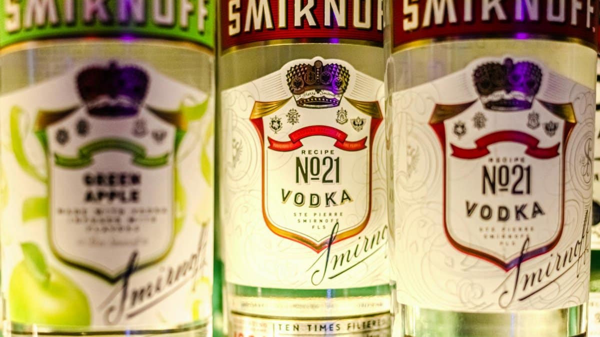 Vibrant close-up of Smirnoff vodka bottles showcasing green apple and classic flavors.