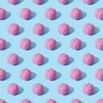 Creative composition of pink brain models in a repeating pattern on a light blue surface, showcasing abstract thinking.