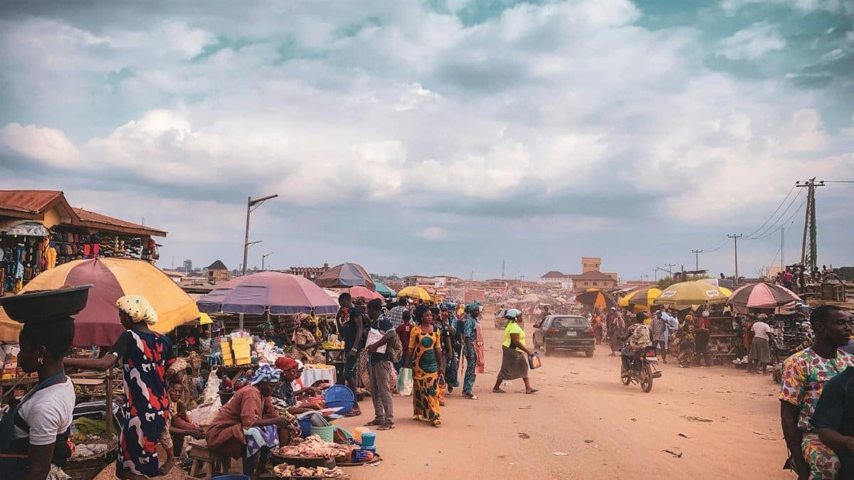 Bustling outdoor market scene in Africa with colorful umbrellas and active local commerce.
