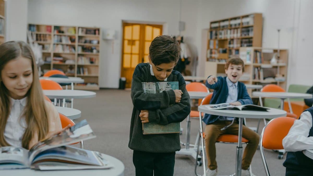A boy being bullied by classmates in a school classroom setting.