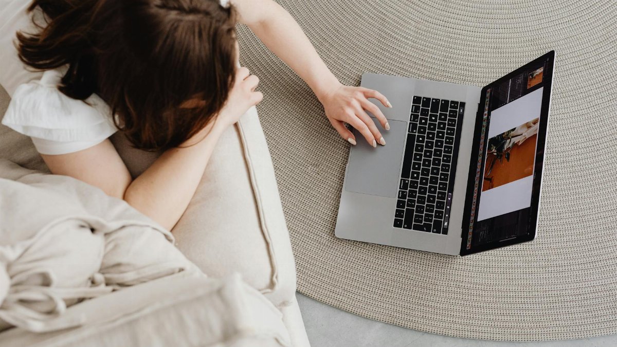 Overhead view of a woman working remotely on a laptop at home, illustrating a modern lifestyle.