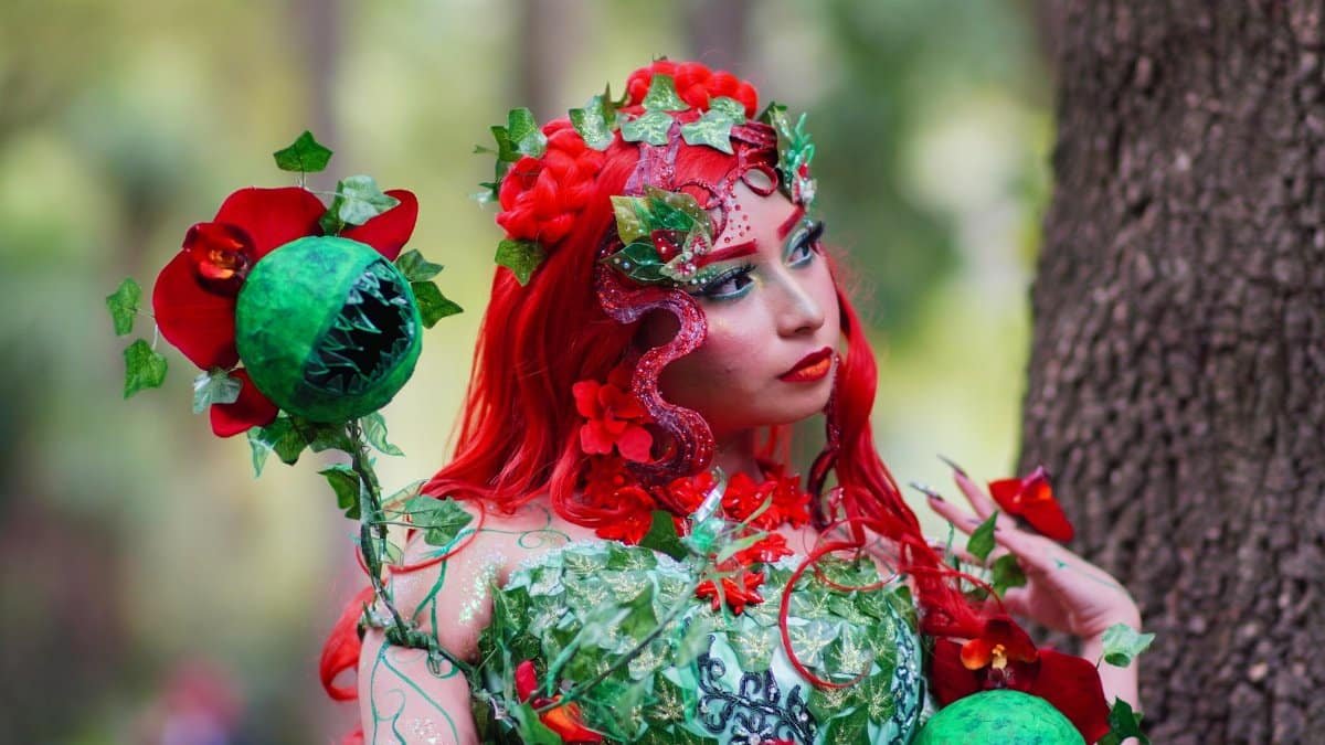 Vibrant cosplay portrait of a woman dressed in a nature-inspired costume with elaborate green and red details.