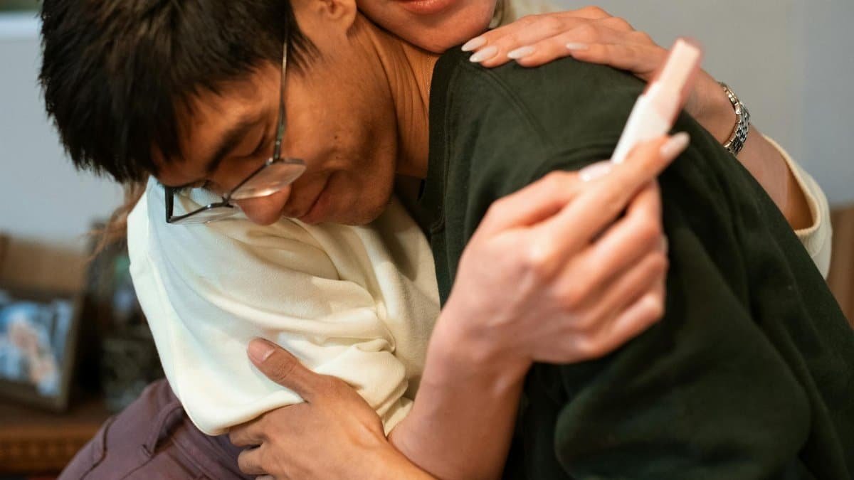 A couple embracing in happiness after discovering a positive pregnancy test result.