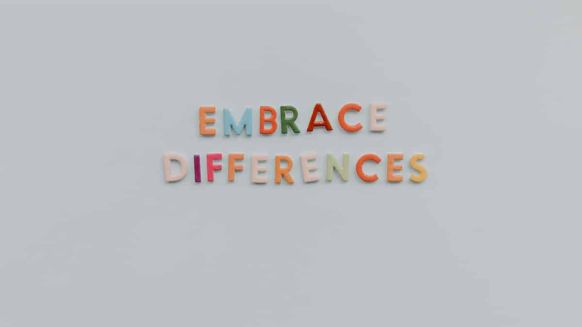 Colorful letters spelling 'Embrace Differences' on a minimalist gray background highlighting inclusivity and diversity.