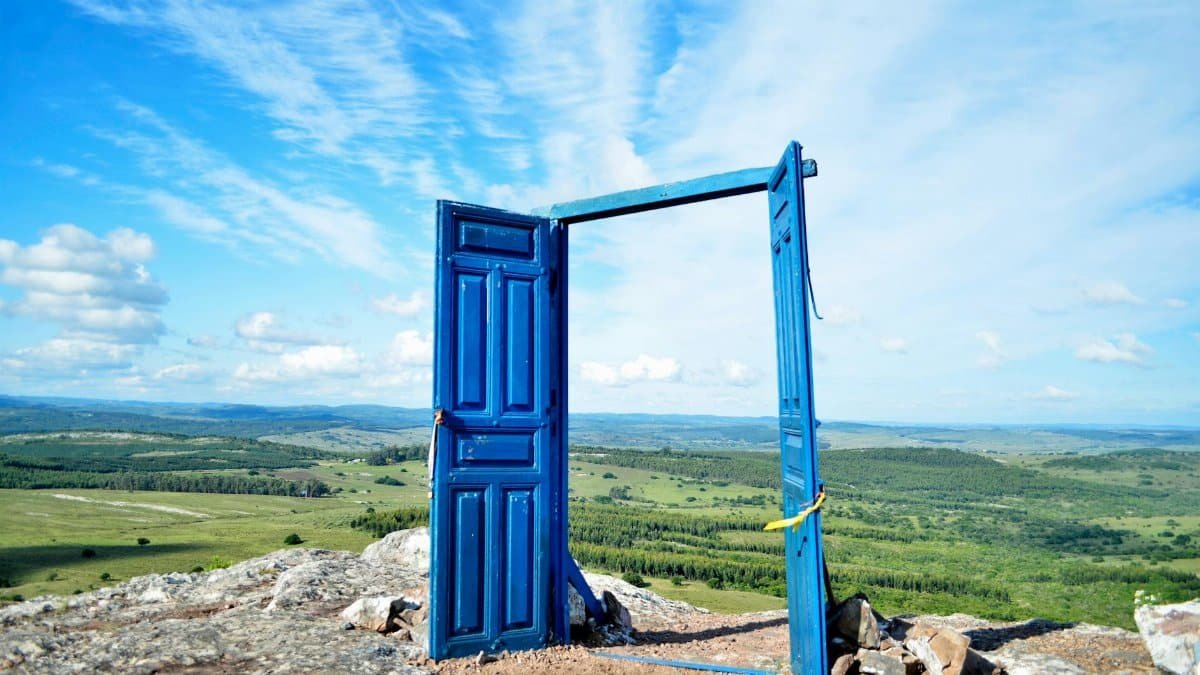 A vibrant blue door frames a scenic landscape in Departamento de Maldonado, Uruguay.