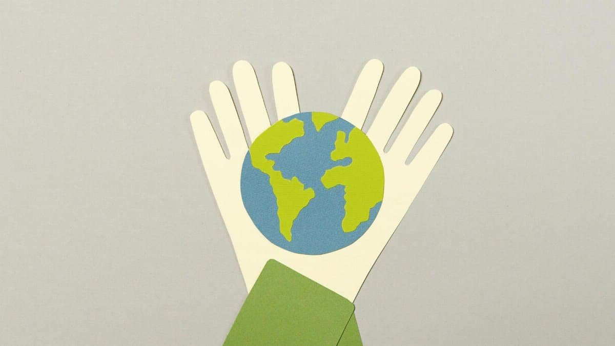 Creative paper cutout art representing Earth held by hands, symbolizes environmental protection.
