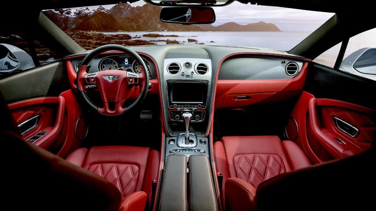 Red leather luxury sports car interior with mountain backdrop outside the window.
