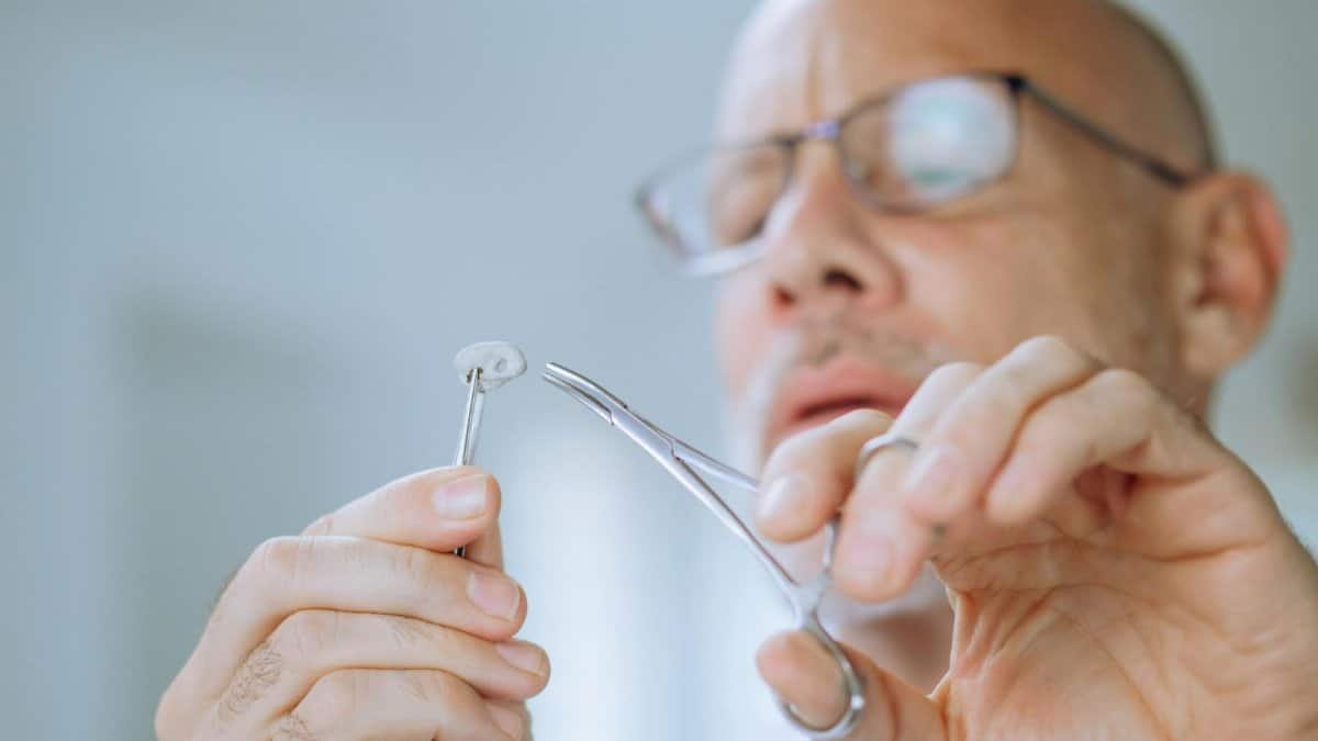Close-up of scientist examining a specimen using tweezers in a laboratory setting.