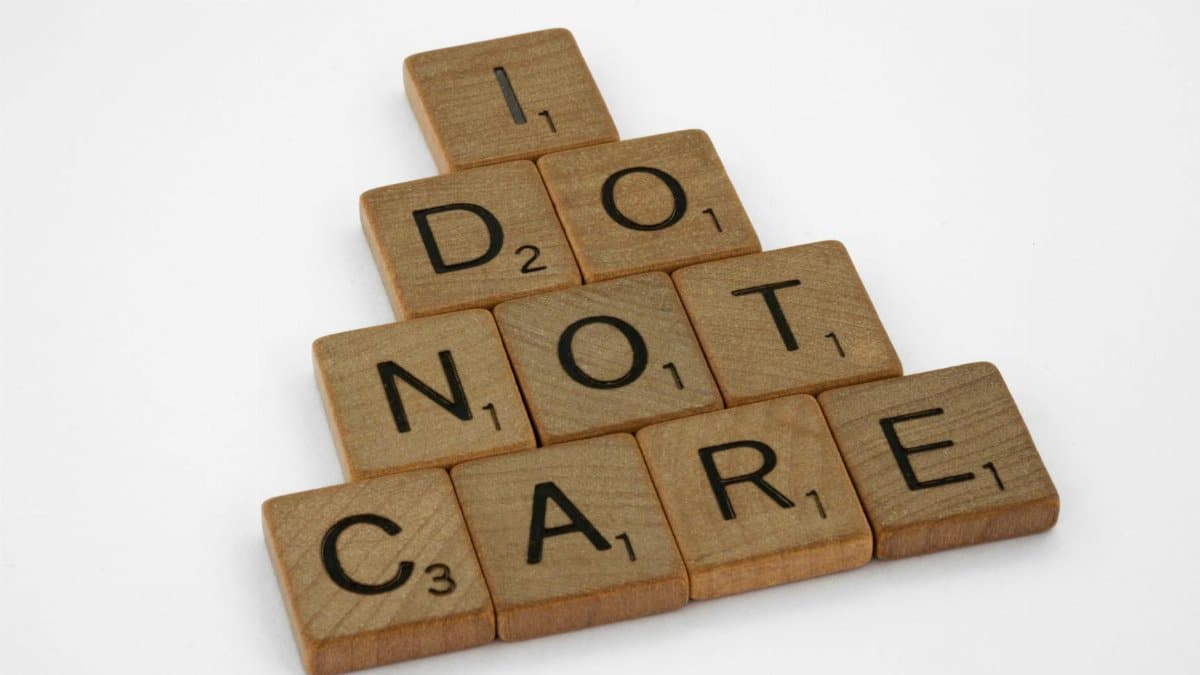 Wooden scrabble tiles arranged to spell 'I Do Not Care' on a clean white surface.