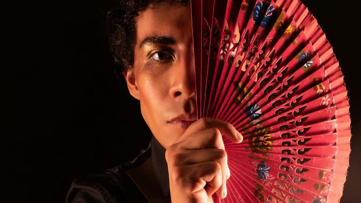 Portrait of a male dancer with a decorative fan, showcasing elegance and expression.