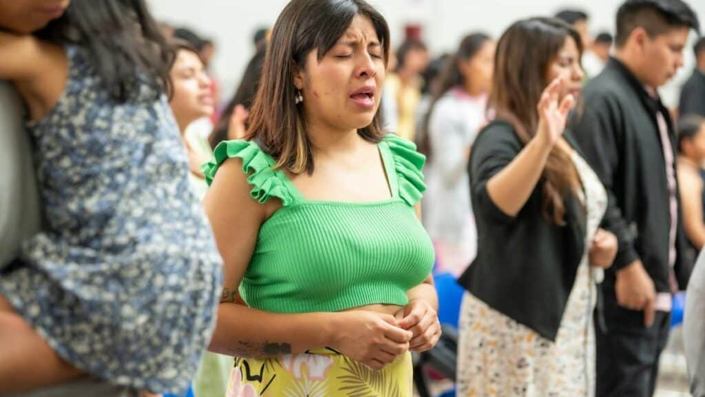 A diverse group of people worshiping indoors in Ciudad de México, expressing devotion and community.