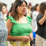 A diverse group of people worshiping indoors in Ciudad de México, expressing devotion and community.