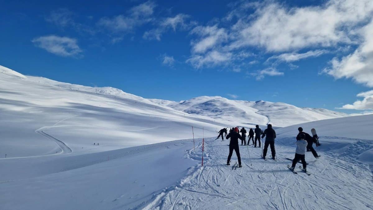 Group of skiers navigating snowy slopes in Hemavan, Sweden under clear blue skies.