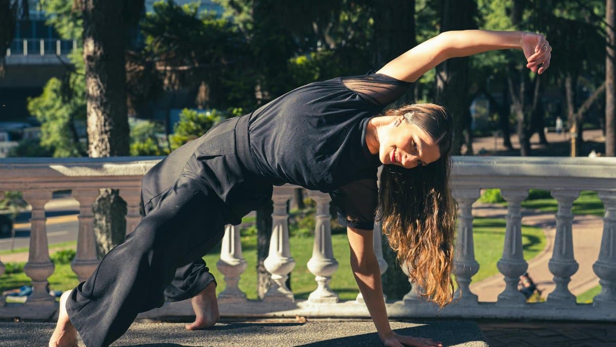 Woman in yoga pose outdoors, showcasing balance and strength in a sunny Buenos Aires park.