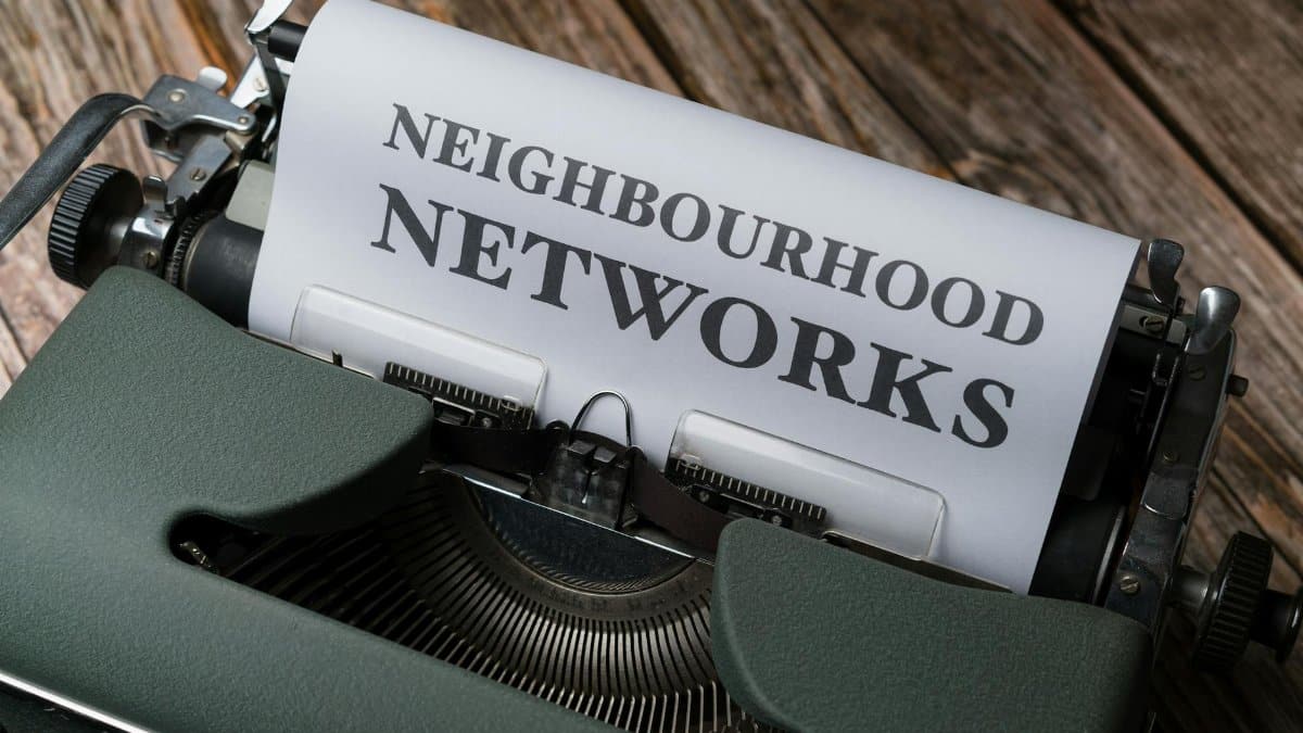 A vintage typewriter displaying the text 'Neighbourhood Networks' on a wooden desk.