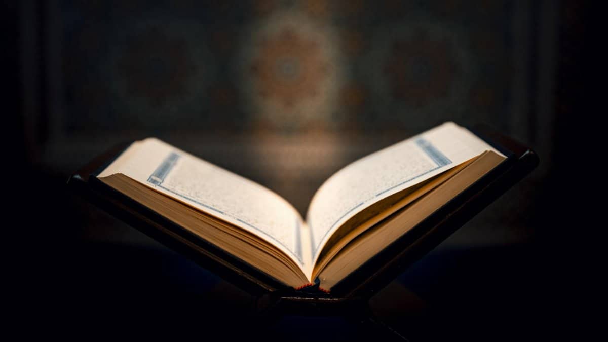 Open Quran on a wooden stand against a decorative background, capturing a spiritual ambiance.