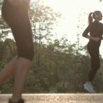 Two women jogging in a sunny park setting, enjoying a healthy morning exercise.