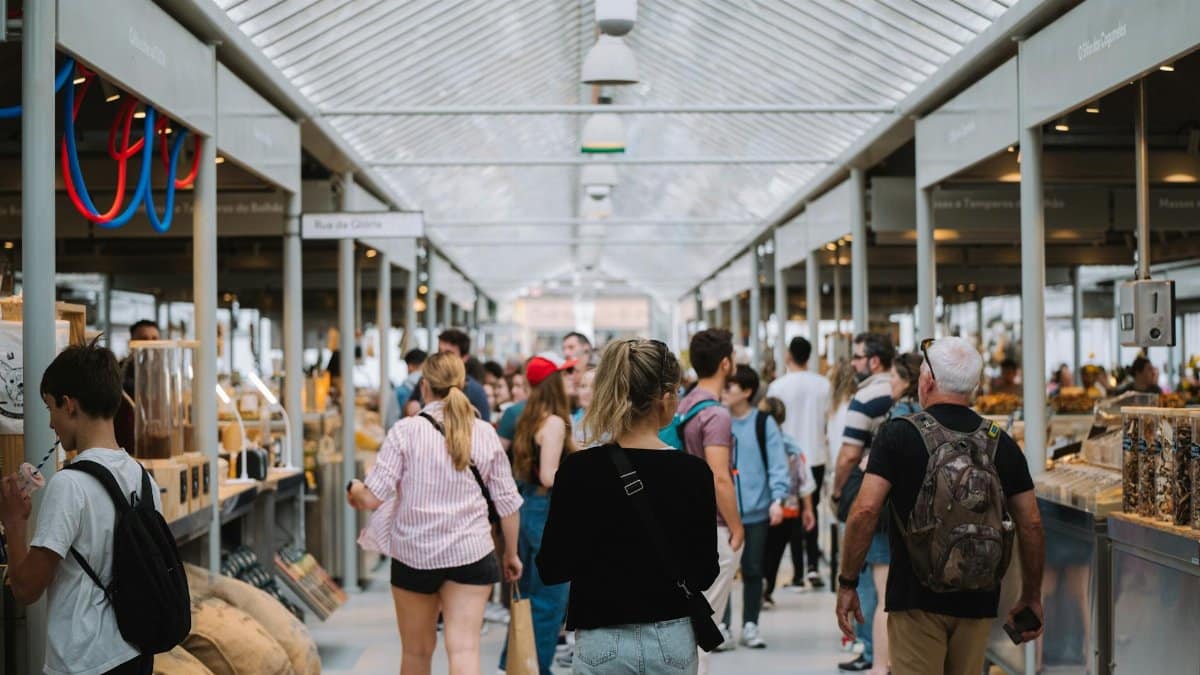 People exploring a vibrant indoor market with modern architecture and diverse stalls.